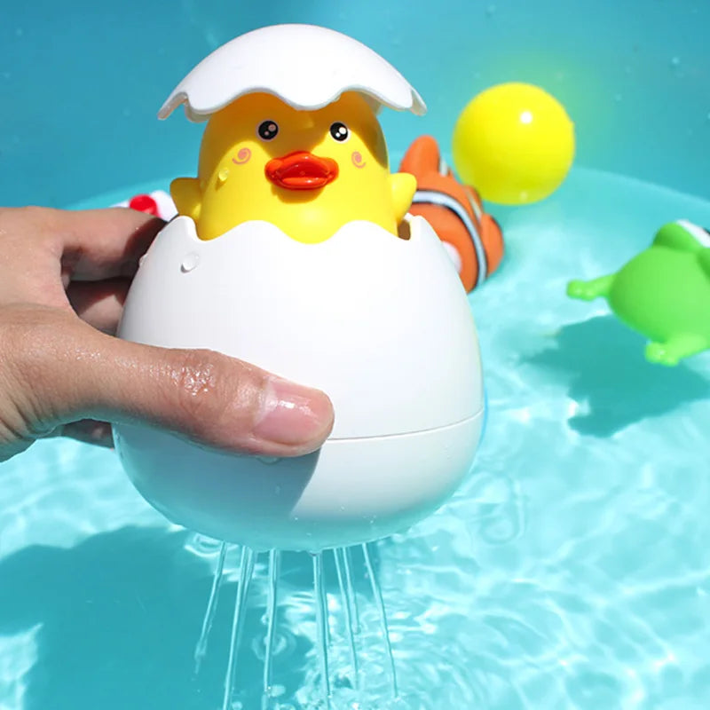 Baby bath toys water spray with a yellow chick emerging from an egg in a pool setting