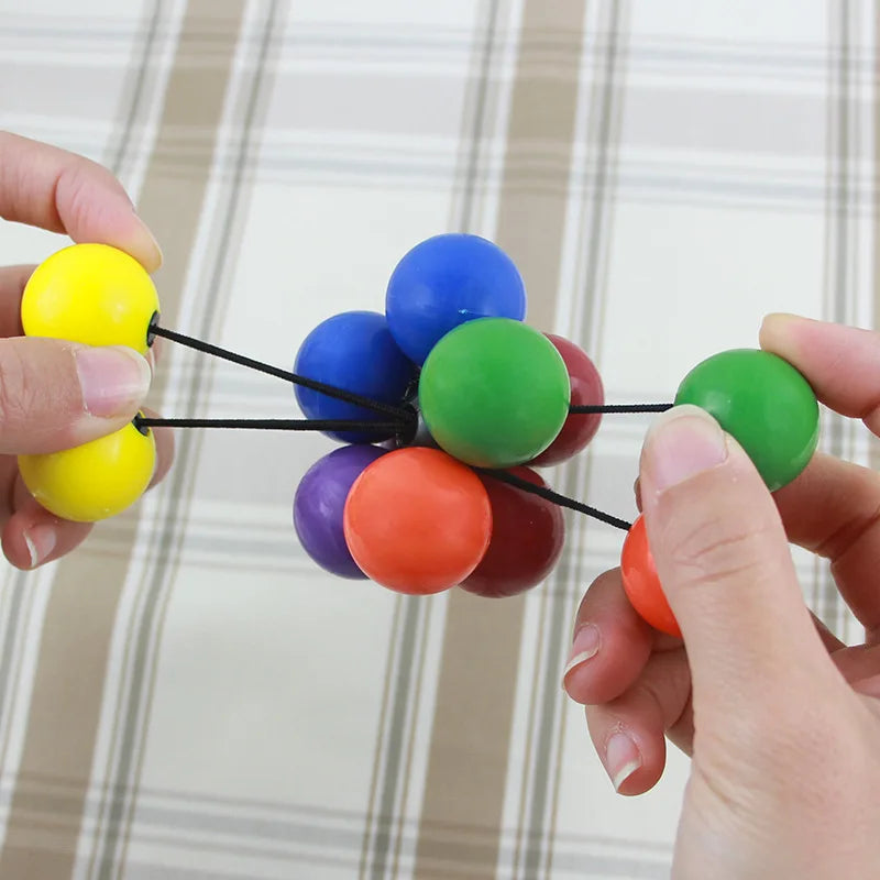 Hands holding a colorful stress relief toy made of soft balls connected by elastic strings