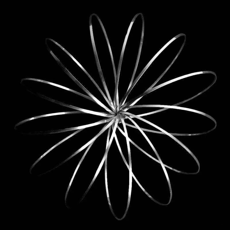 Silver kinetic flow ring toy expanding in circular loops on black background