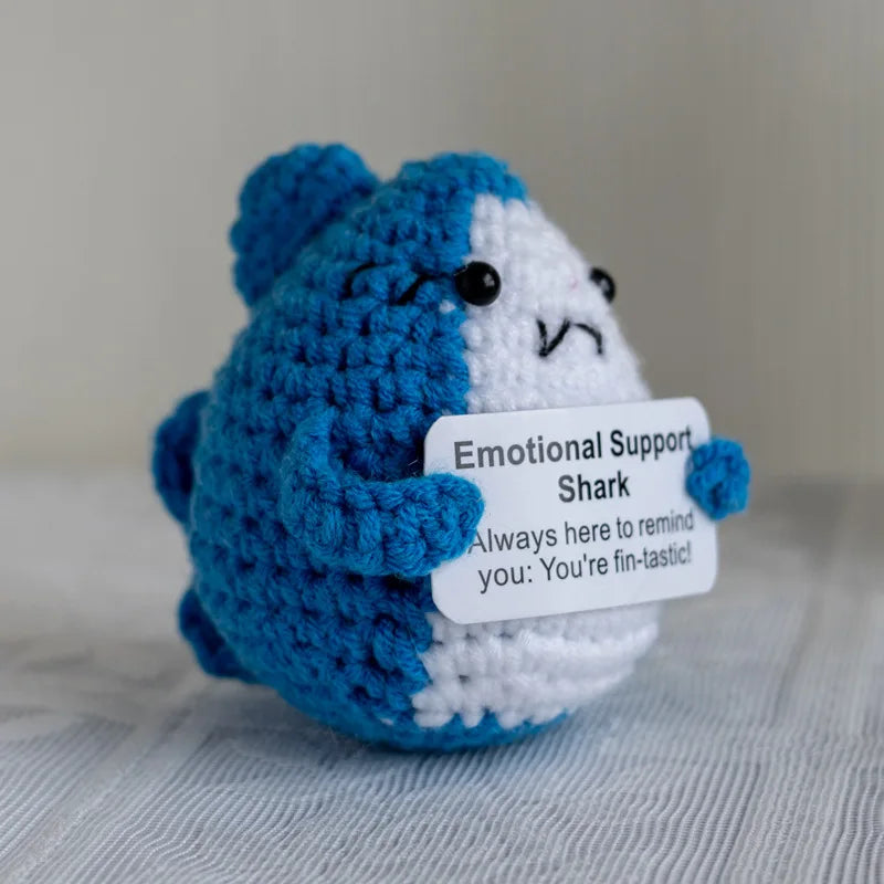Handmade crochet emotional support buddies in the shape of a shark with a supportive message