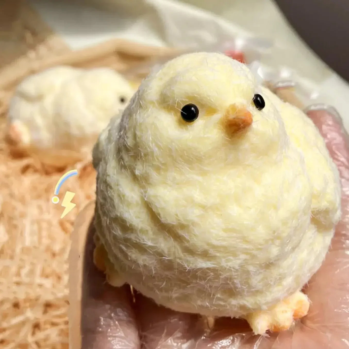 A hand in a plastic glove squishes a fluffy yellow chick among many similar chick figures, showcasing their soft texture and round shape.