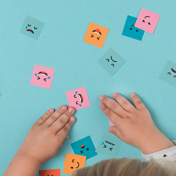 Child using Montessori tools for emotional intelligence with colorful paper faces showing different emotions