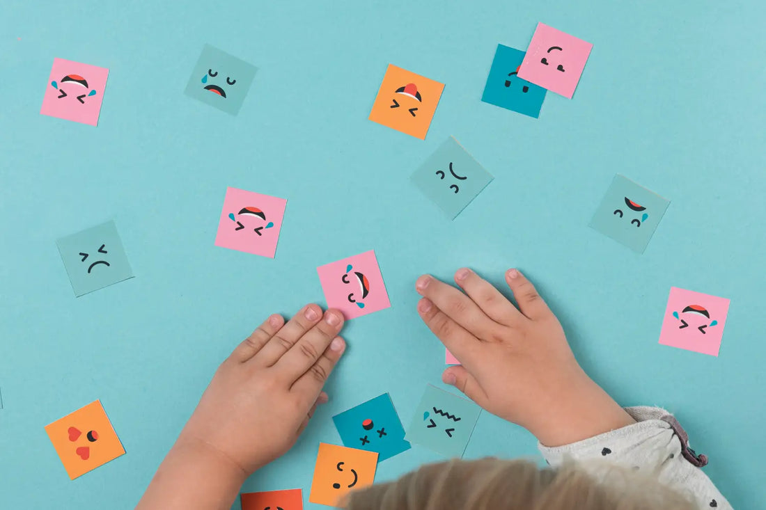 Child using Montessori tools for emotional intelligence with colorful paper faces showing different emotions