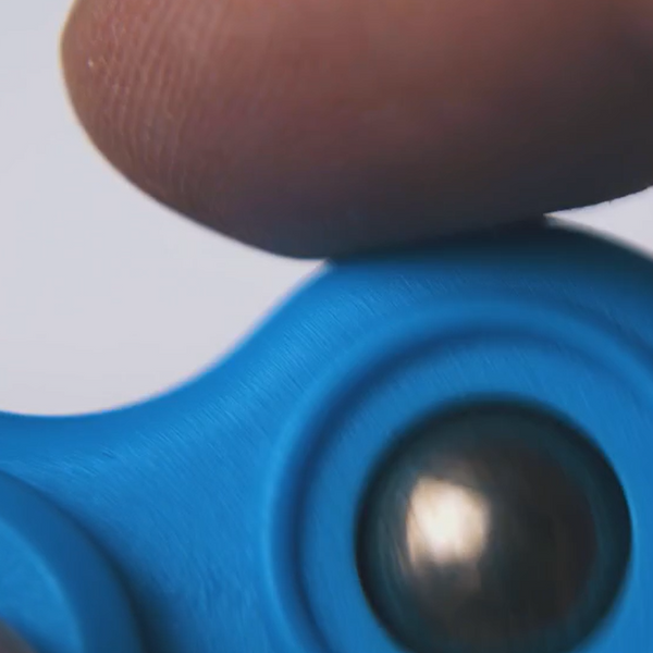 Close-up of a blue fidget spinner held by a finger showing what are fidget toys in detail