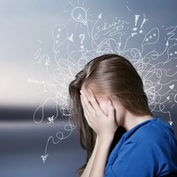 Young woman covering face with hands surrounded by drawn question marks and ideas illustrating is ADHD considered a disability