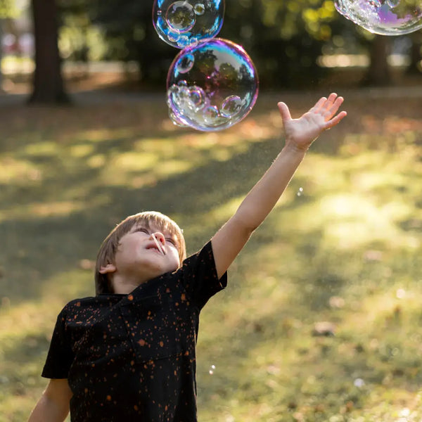 toddler reaching for floating bubbles outdoors