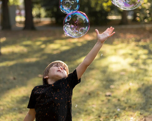 toddler reaching for floating bubbles outdoors