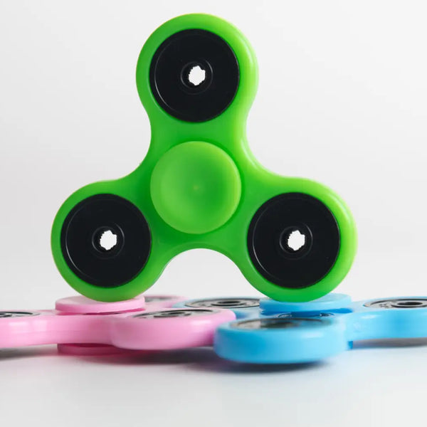 Green, pink, and blue fidget spinners demonstrating the therapeutic benefits of fidget tools for stress relief