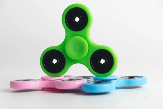 Green, pink, and blue fidget spinners demonstrating the therapeutic benefits of fidget tools for stress relief