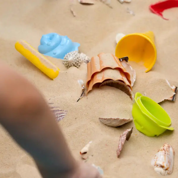 Children playing with colorful sand toys and shells in outdoor sensory activities for autism