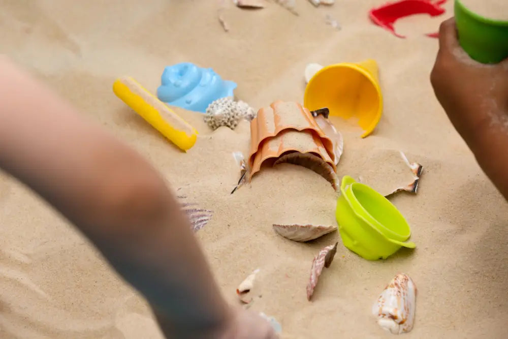 Children playing with colorful sand toys and shells in outdoor sensory activities for autism