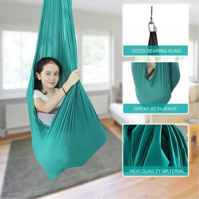 Child sitting in a teal stretchy compression sensory swing indoors