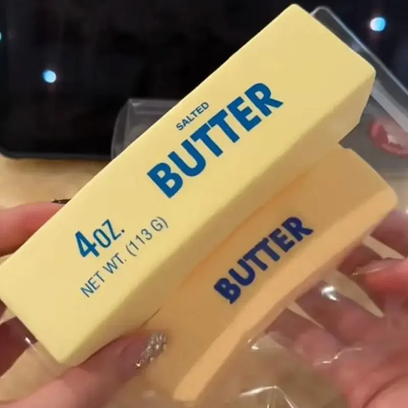 Hand squishing a stretchy butter stick squeeze toy