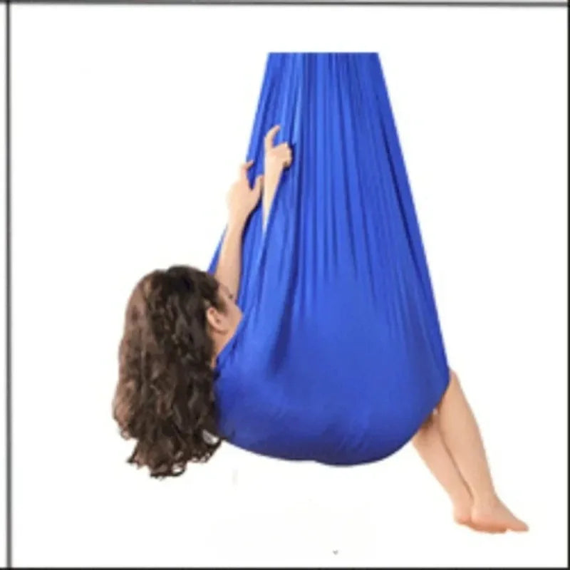 Child hanging in a blue stretchy compression sensory swing