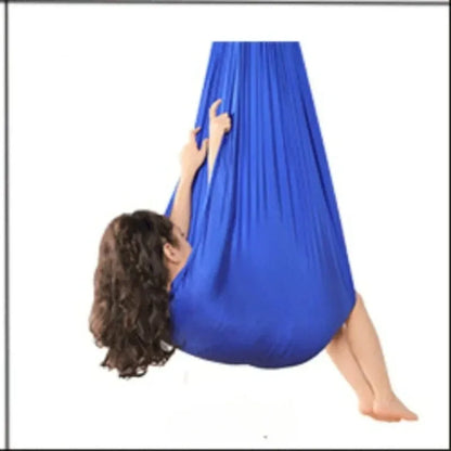 Child hanging in a blue stretchy compression sensory swing