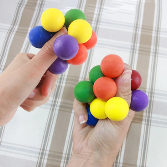 Hands squeezing colorful stress relief toy made of soft, bouncy balls for sensory play and relaxation