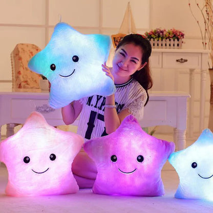 Child holding glowing LED plush cushion star toys in pastel colors with smiling faces