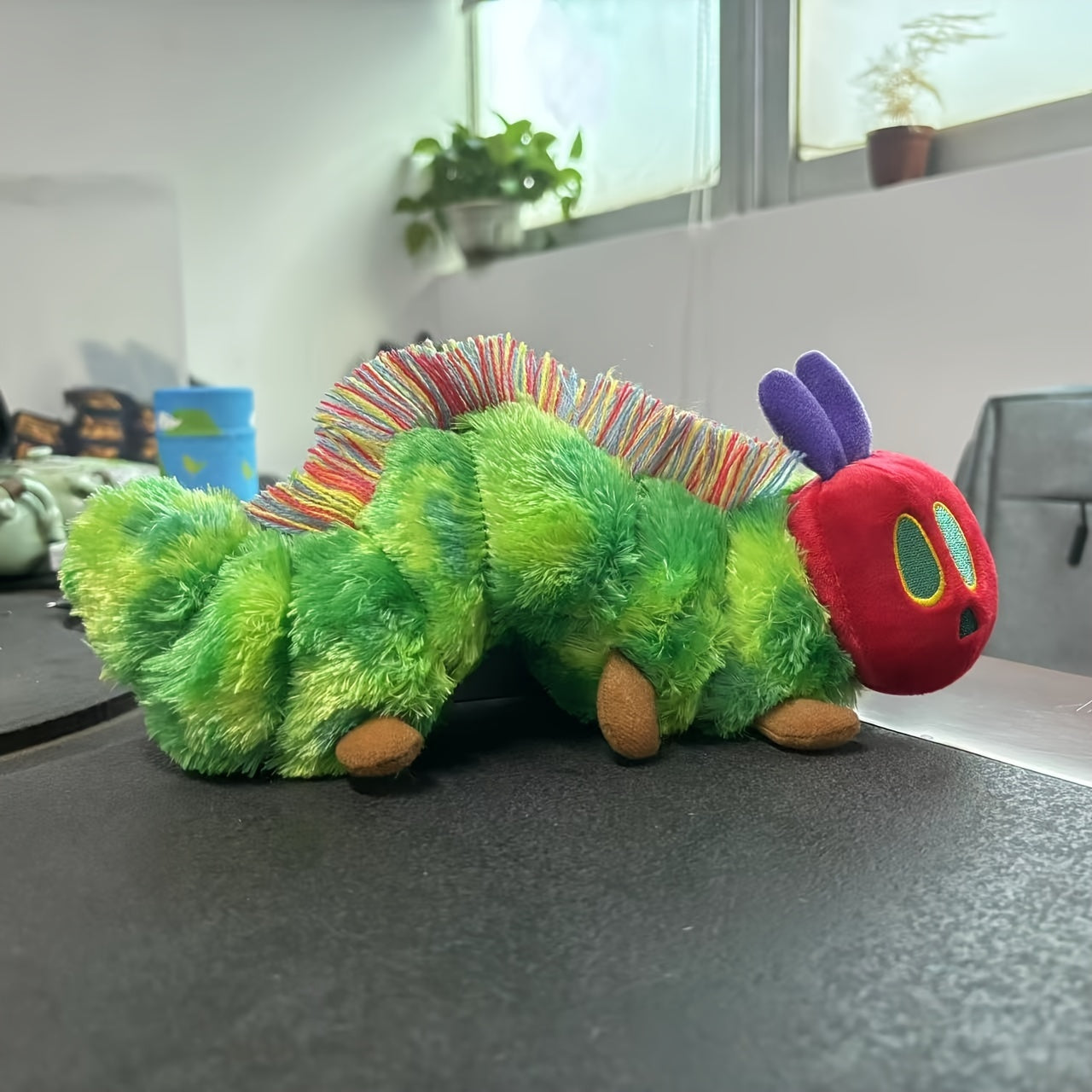 Green caterpillar plush toy with red face and colorful antennae by Active Playthings