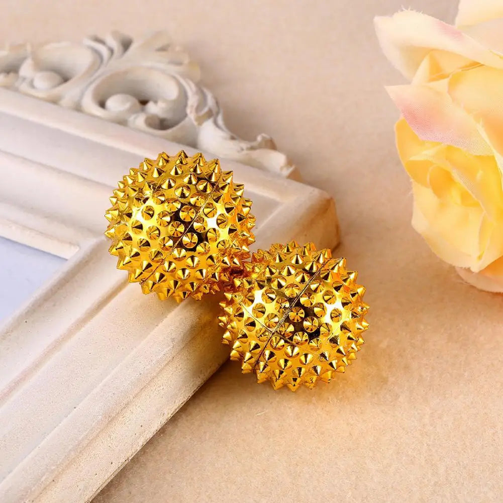 Pair of golden magnetic acupoint massage balls with spiky texture for relaxation and therapy