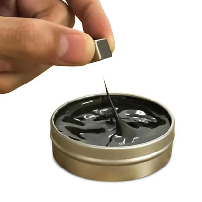 Hand holding a magnet above magnetic ferrofluid playdough in a tin, showcasing its magnetic properties