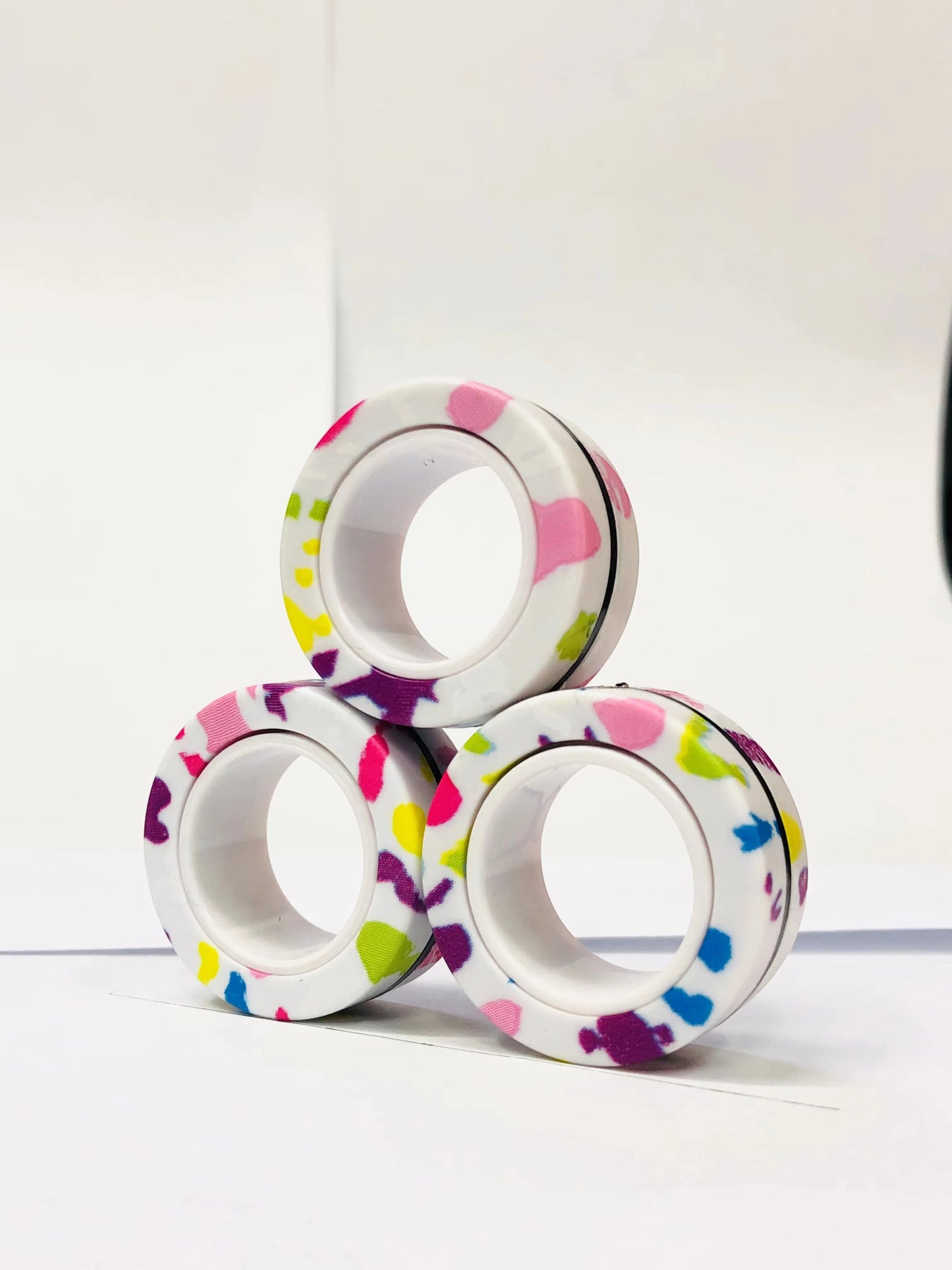 Colorful patterned magnetic finger ring fidget toy stacked in a triangle for stress relief and focus