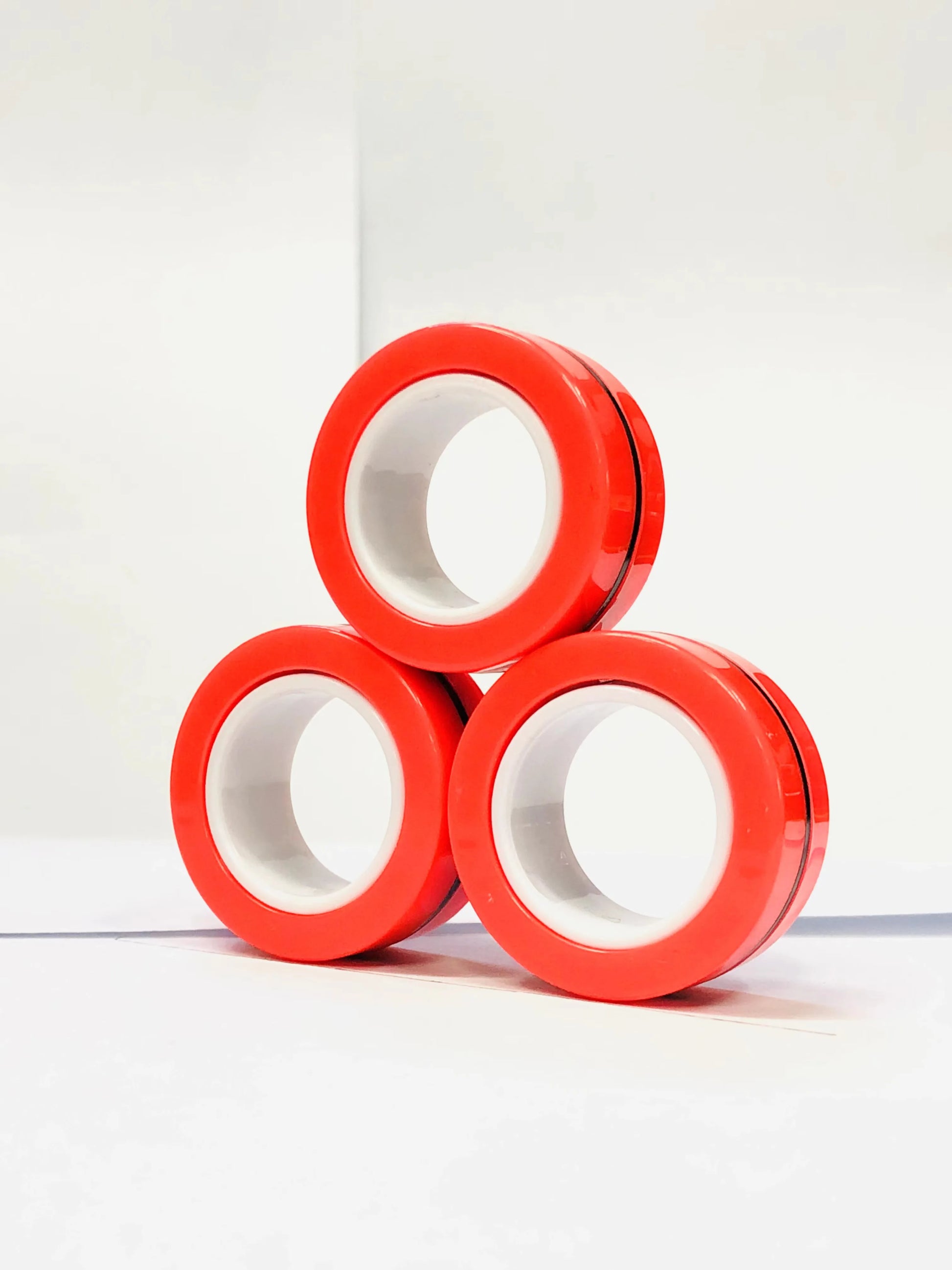Three red magnetic finger ring fidget toys stacked in a triangular shape for stress relief and focus