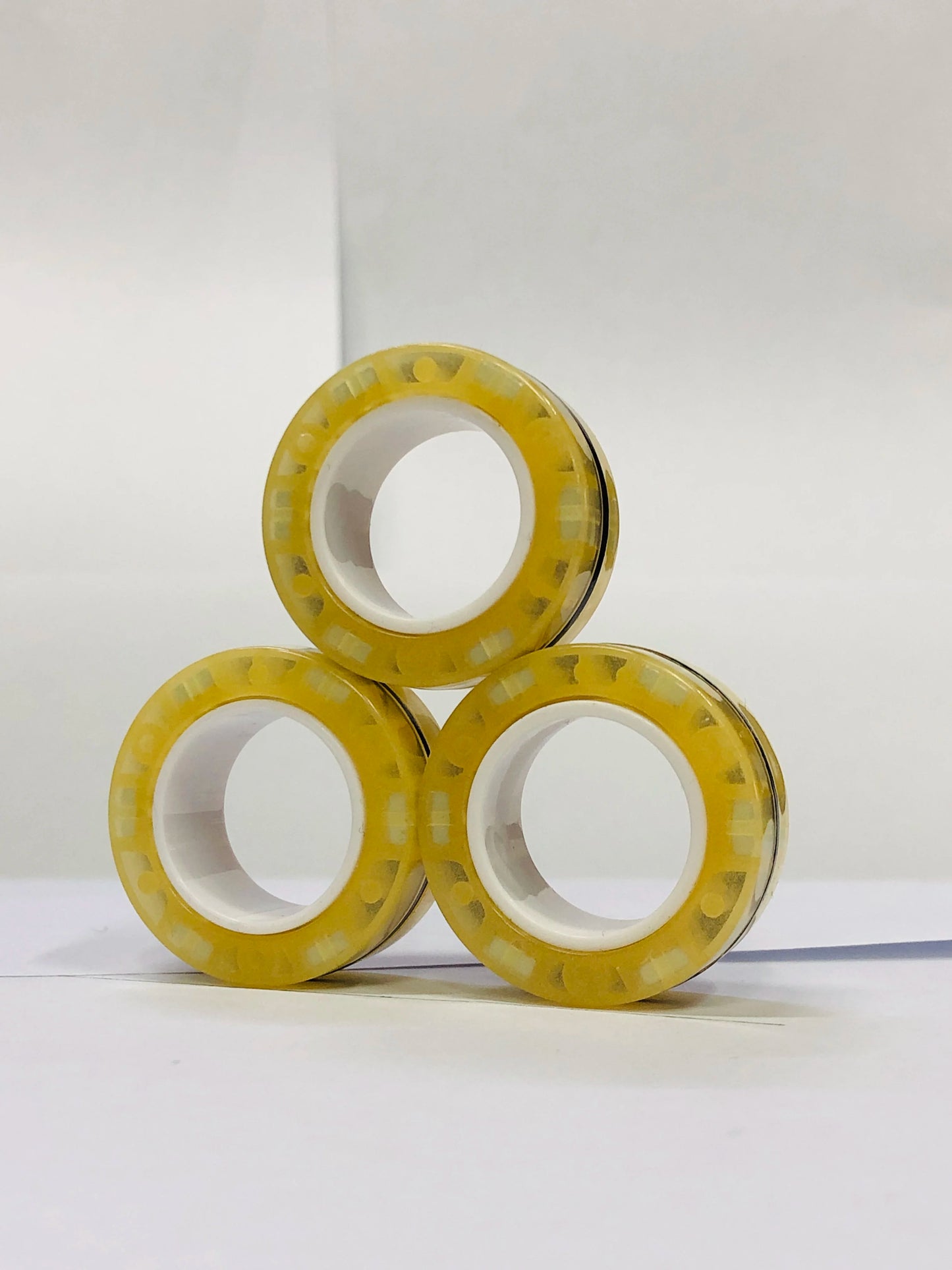 Three yellow magnetic finger ring fidget toys stacked in a triangle formation for stress relief