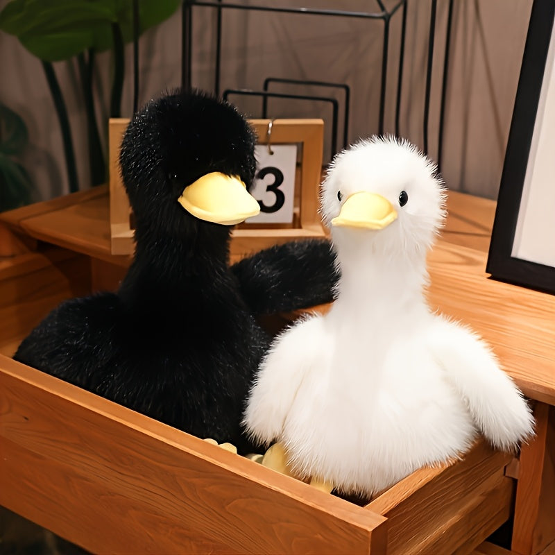 Two snuggly duck plush toy stuffed animals in black and white sitting inside a wooden drawer