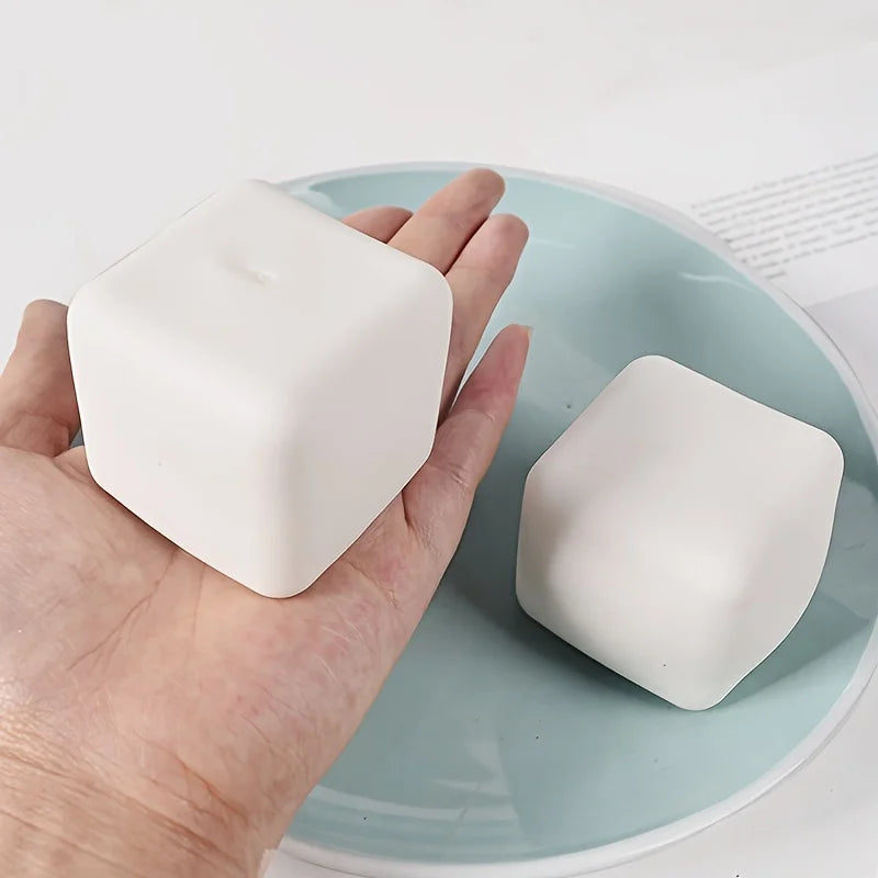 Hand holding a squishy tofu stress ball on a light blue plate, perfect for stress relief