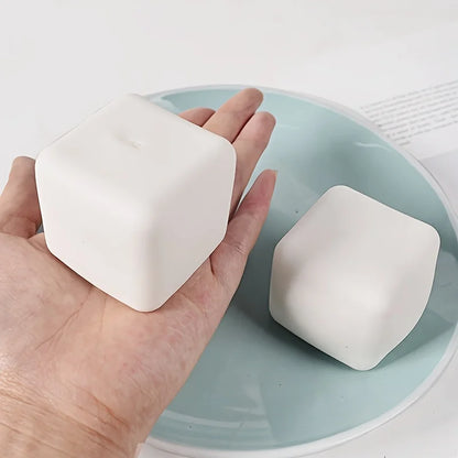 Hand holding a squishy tofu stress ball on a light blue plate, perfect for stress relief